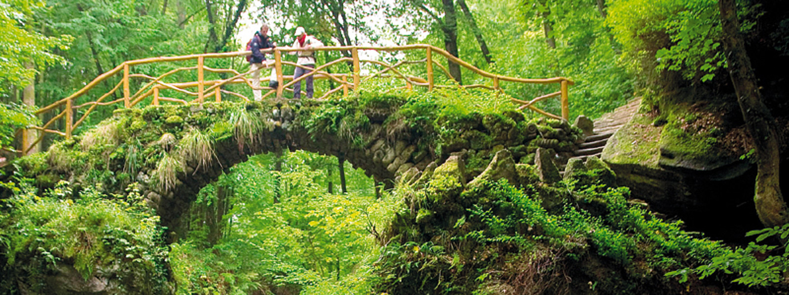 Wanderer auf Brücke über Wasserfall